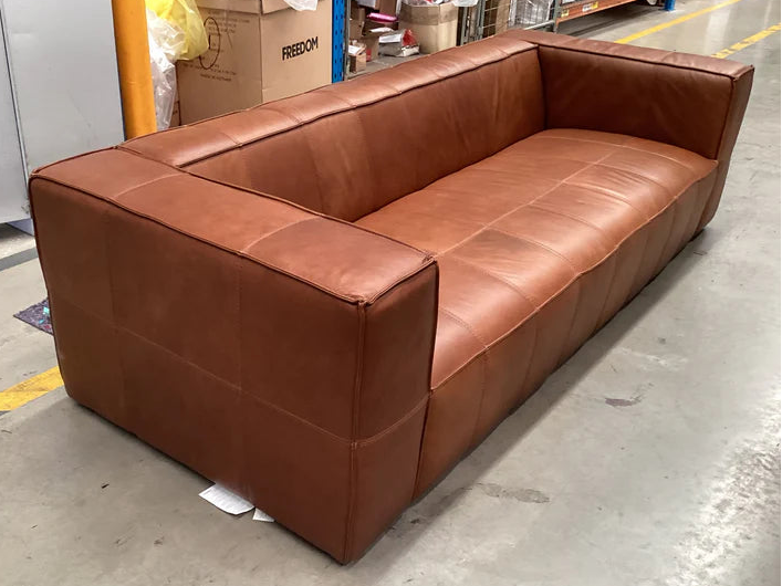 Brown leather sectional sofa in a warehouse setting