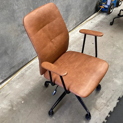 Brown office chair on wheels in a room with concrete floor and wall.